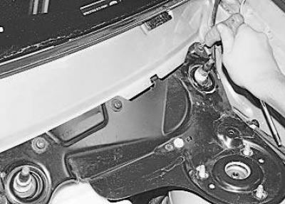 4. Отверните три гайки крепления амортизаторной стойки…