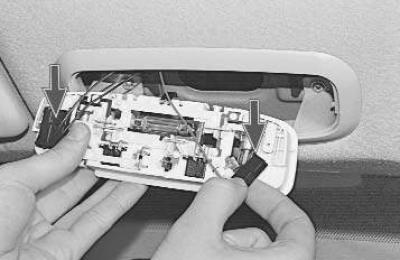 4. Отожмите отверткой фиксаторы плафона и извлеките плафон из обивки потолка.