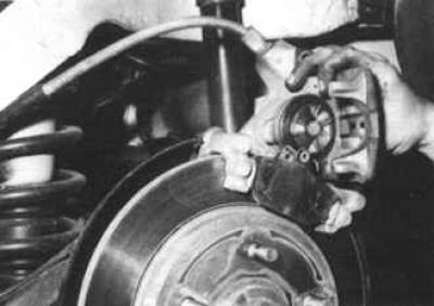 6. Unscrew and remove the front bolt securing the caliper to the bracket, holding the caliper guide…